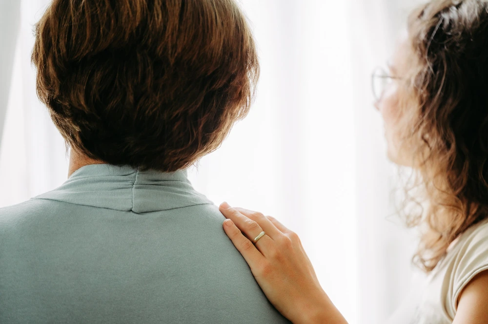 Ingrid Fankhauser legt einer Dame unterstützend die Hand auf die Schulter